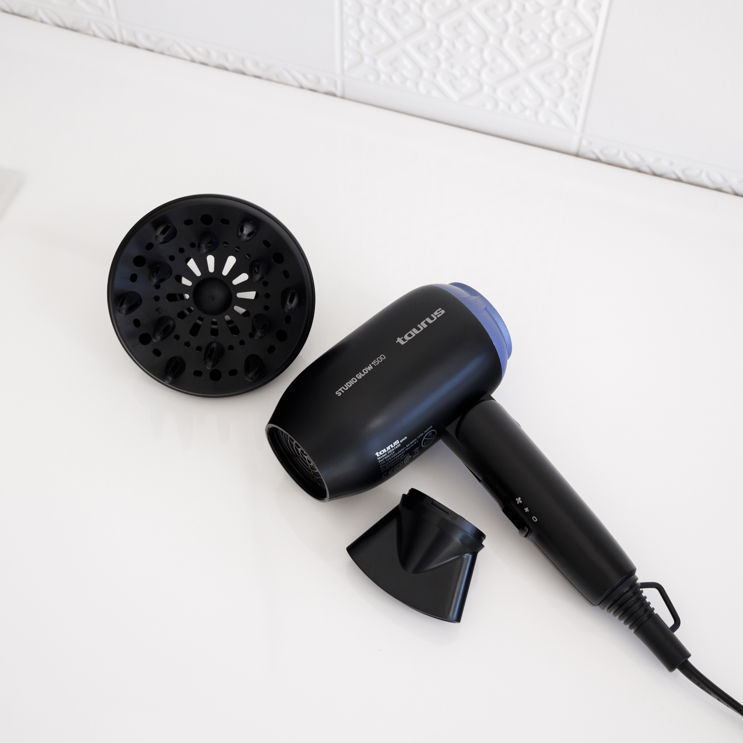 Secador de pelo negro con accesorios, sobre superficie blanca, con la marca Taurus visible.