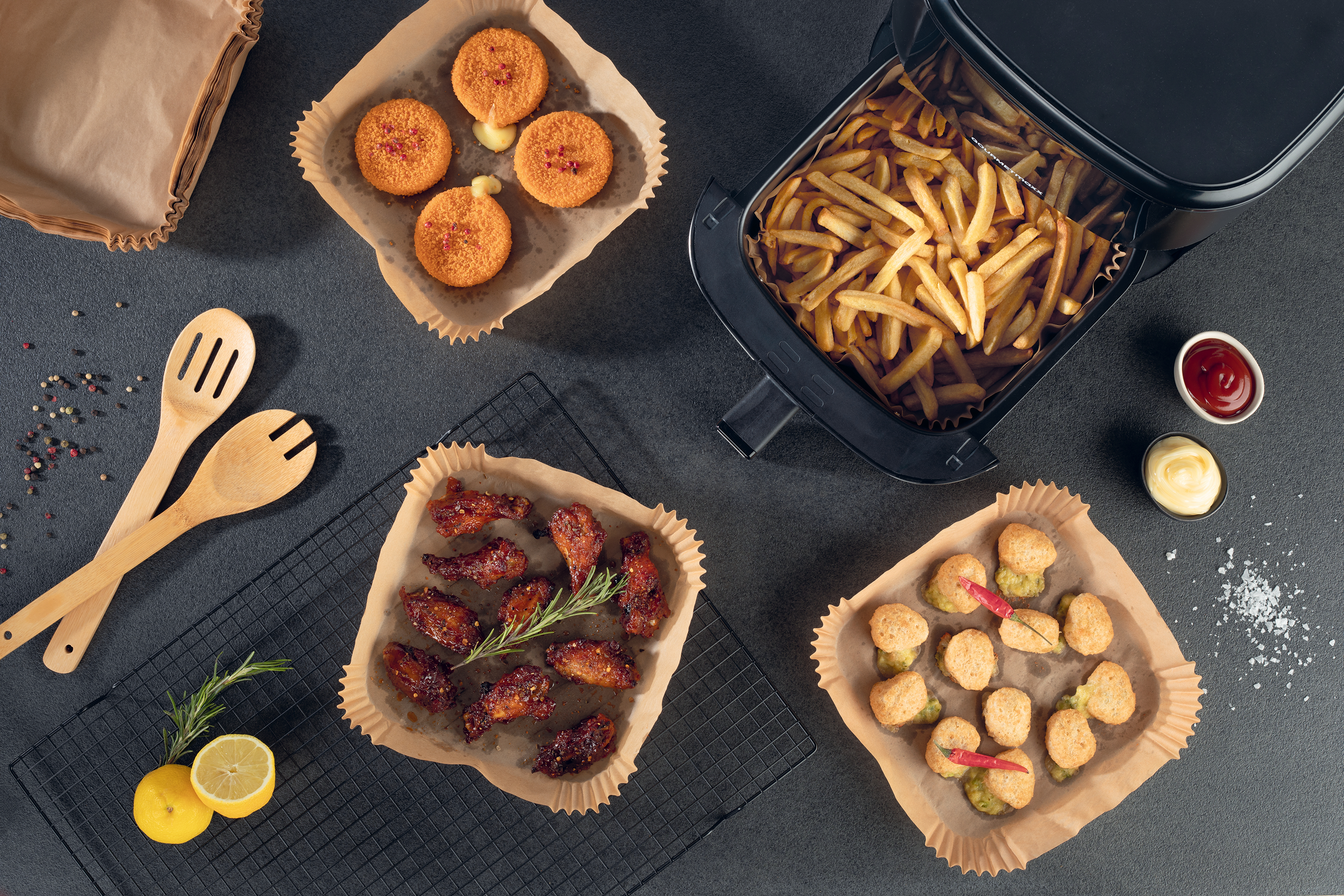 Heißluftfritteuse gefüllt mit Essen. Enthält Pommes, Hähnchenflügel und andere frittierte Artikel.