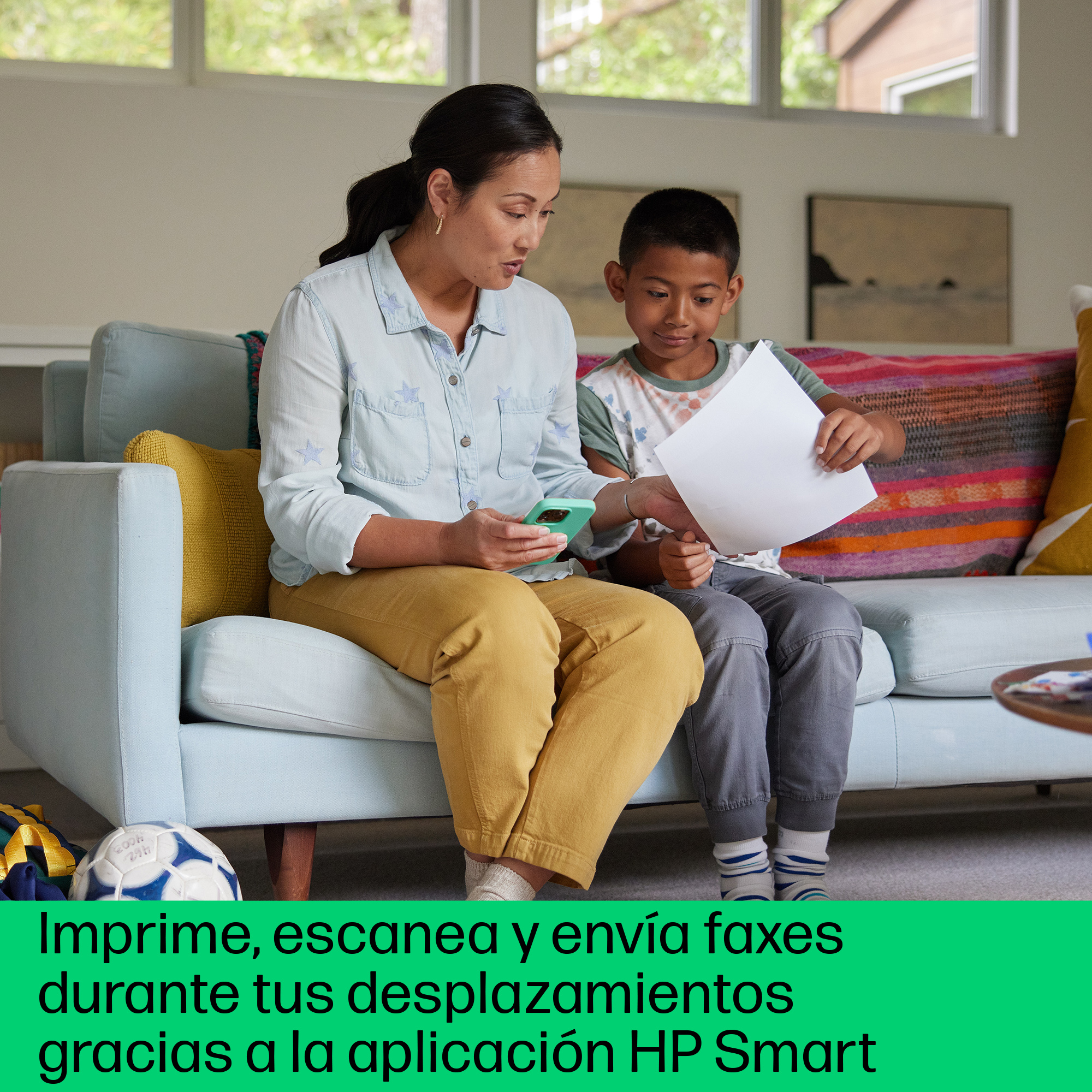 Una mujer y un niño en un sofá. El niño sostiene un papel, la mujer un teléfono.