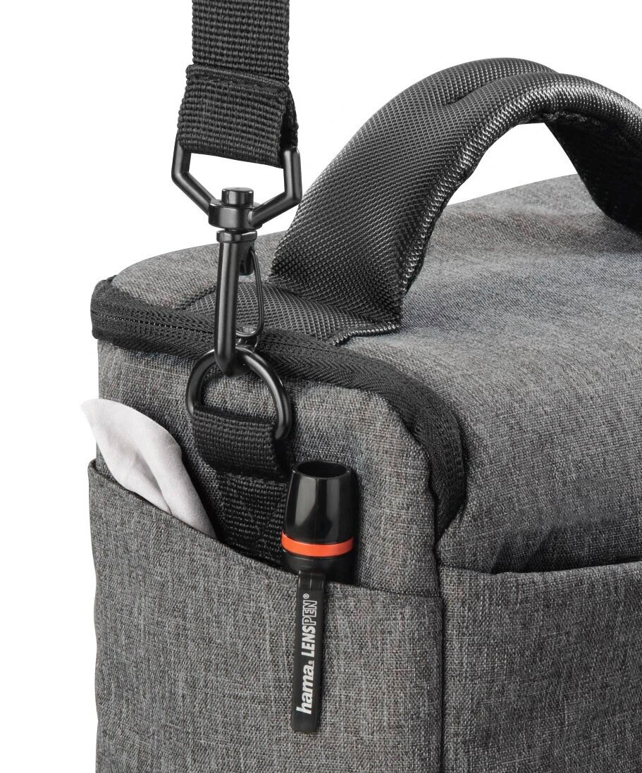 Zbliżenie szarej torby na aparat z piórem do obiektywu, kieszenią i czarnym paskiem na ramię.