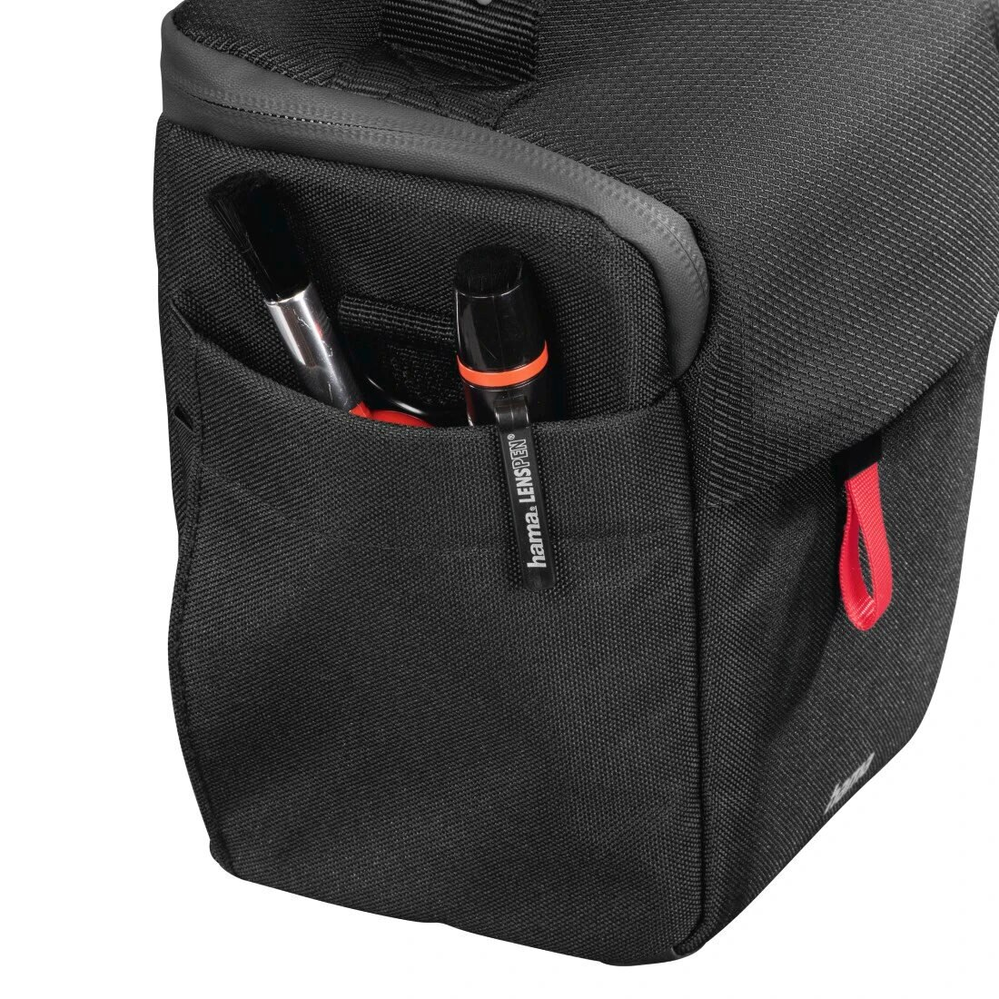 Czarna torba na aparat z kieszenią, mieszcząca dwa długopisy. Na torbie widoczny jest czerwony pasek.