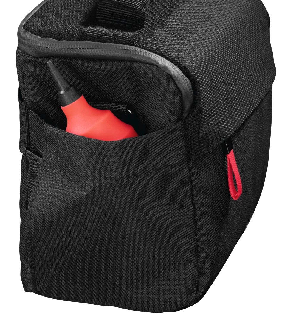 Czarna torba na aparat z czerwoną gruszką widoczną w bocznej kieszeni.