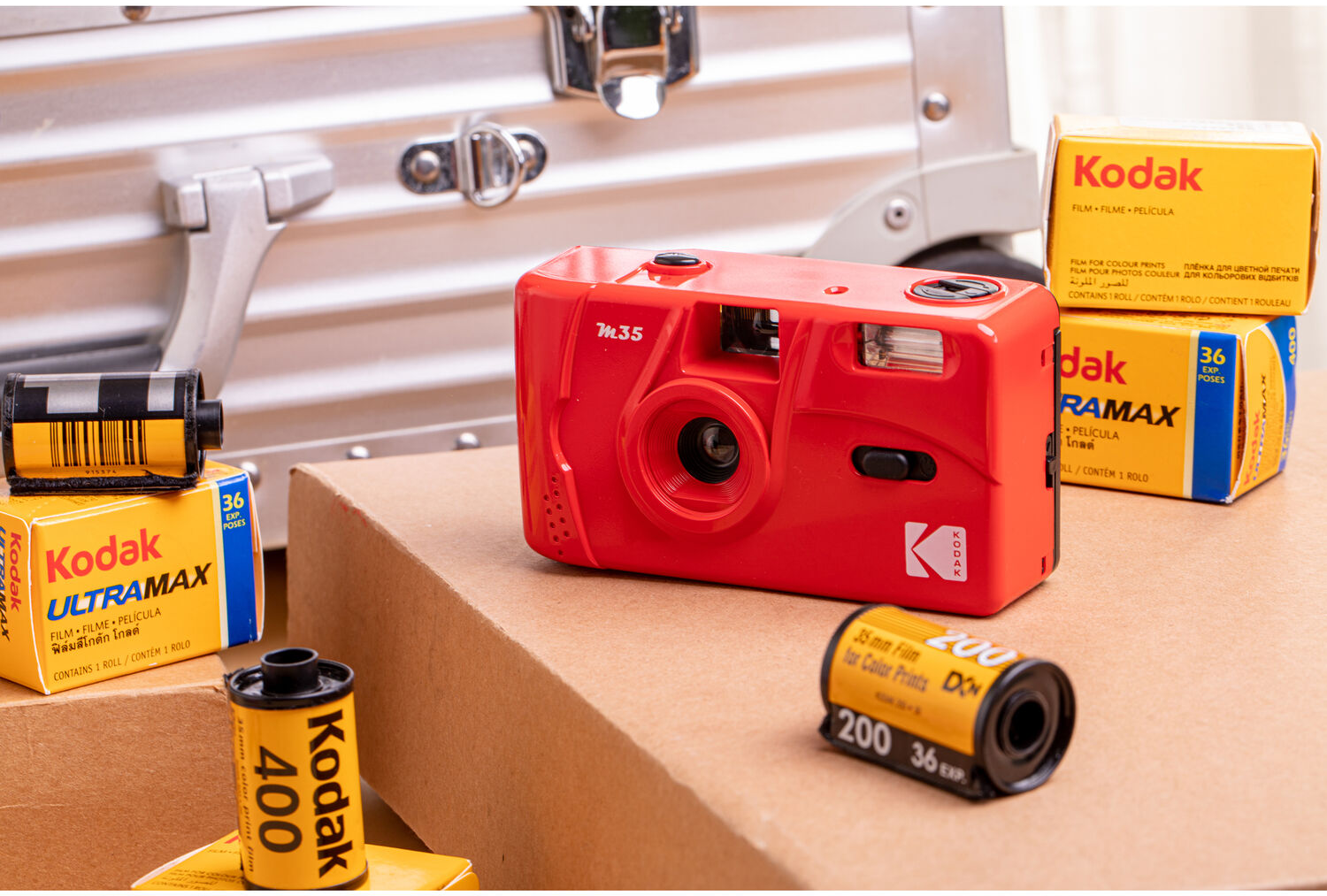Piros kamera filmtekercsekkel. Kodak kamera és filmtekercsek barna felületen.