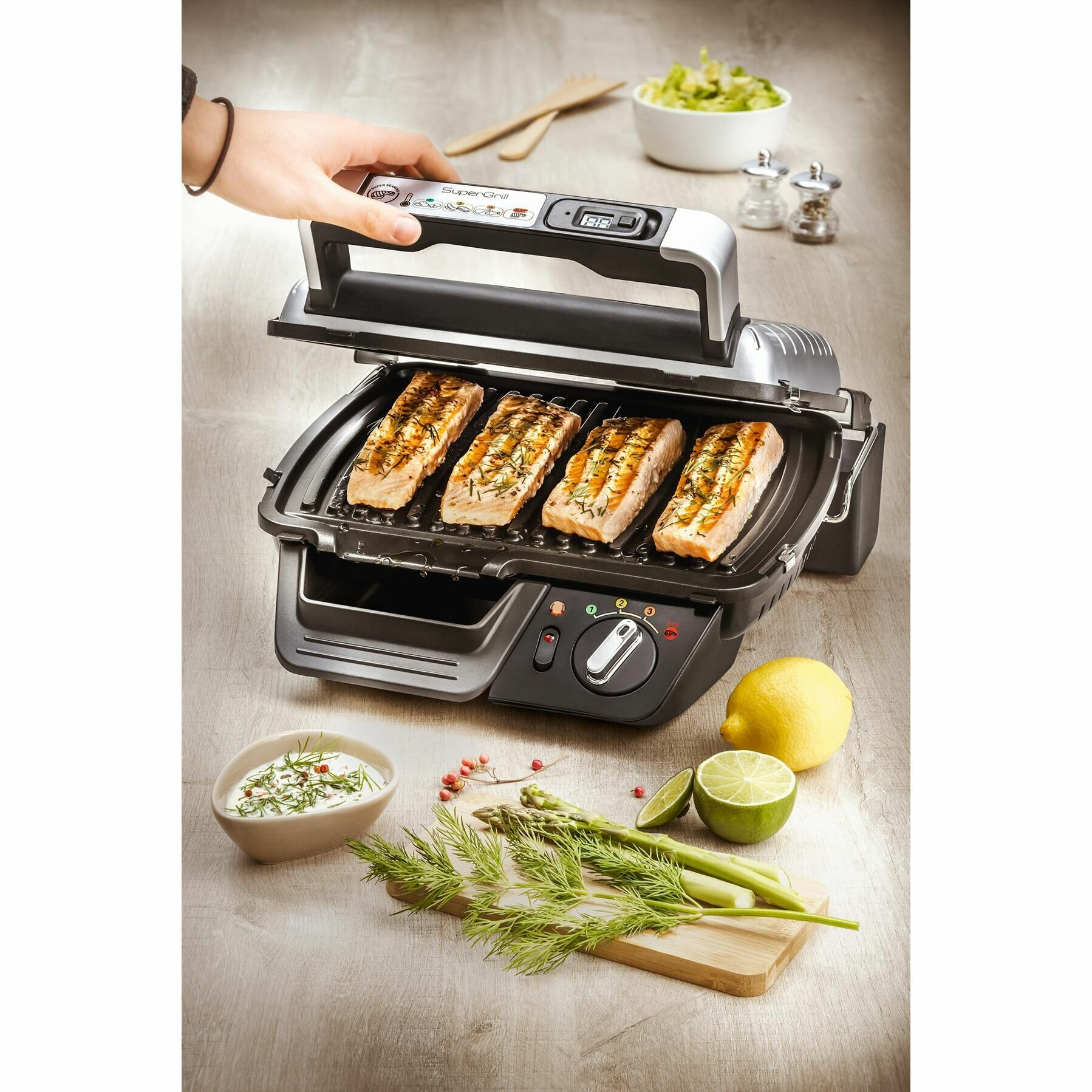 Grill z łososiem, cytryną i ziołami, z ręką osoby na górze.