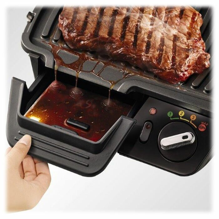 Smażony stek na czarnym grillu. Sok spływa do tacy poniżej.