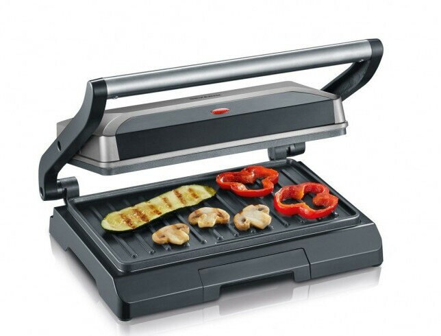 Grill z grillowanymi warzywami. Otwarty, widoczne warzywa. Srebrny uchwyt, czarna podstawa.