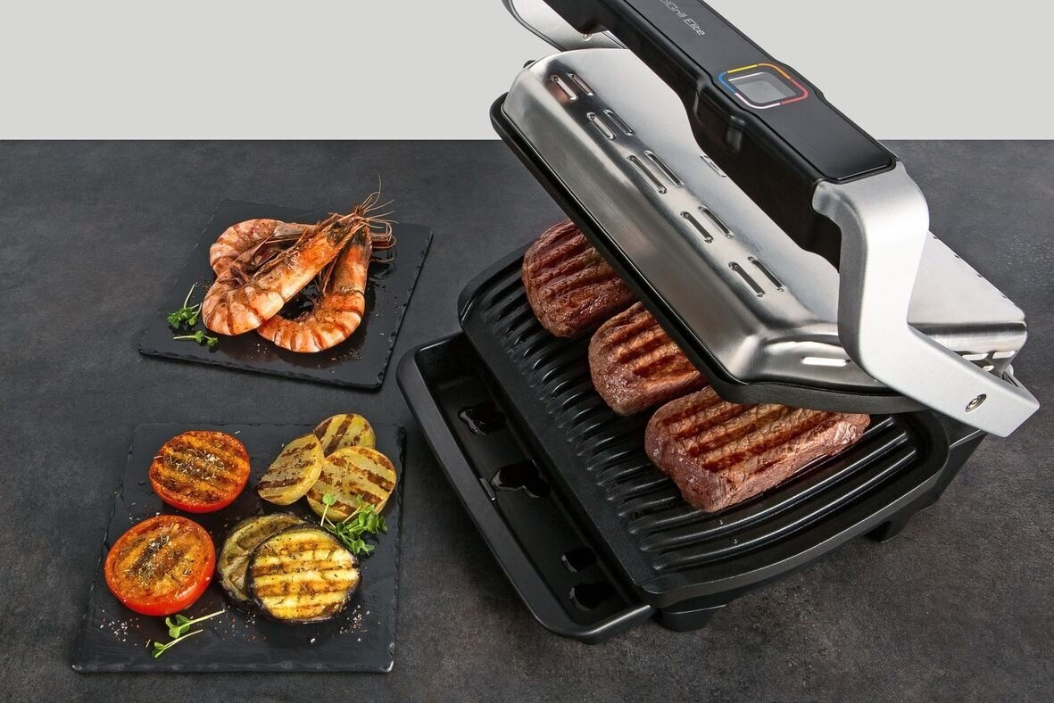 Grill z grillowanym jedzeniem. Krewetki, pomidory i mięso na czarnych talerzach.