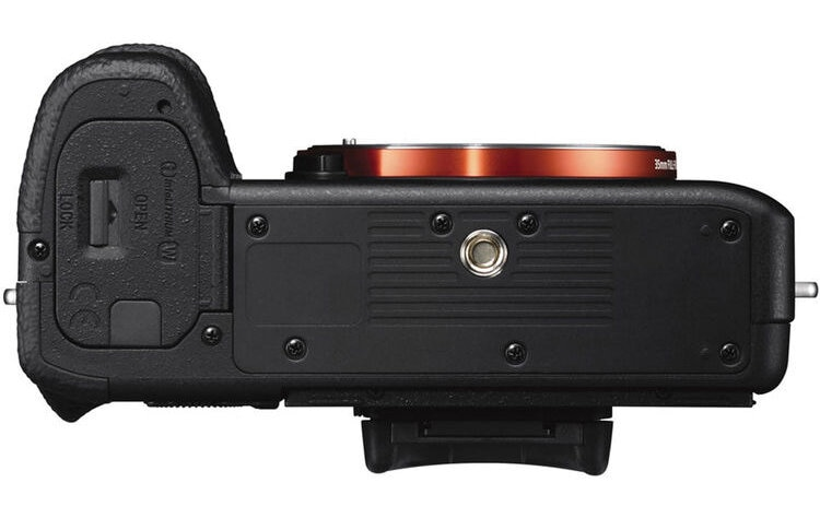 Widok z góry czarnego aparatu z pomarańczowym mocowaniem obiektywu. Przyciski, uchwyt i otwarte komory.