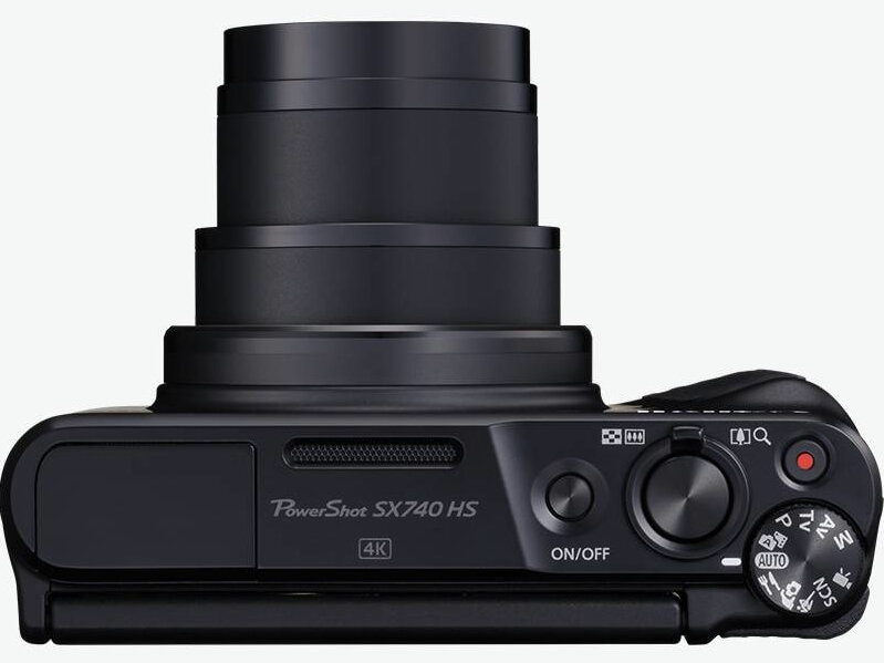 Czarny aparat, widok z góry. Ma przyciski, pokrętło i obiektyw zoom.