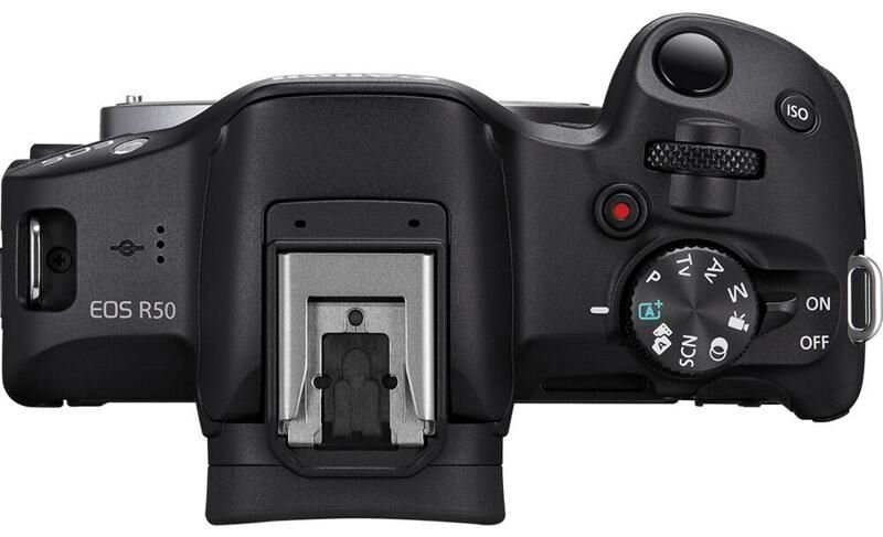 Widok z góry czarnego aparatu Canon EOS R50 z pokrętłami, przyciskami i mocowaniem lampy błyskowej.