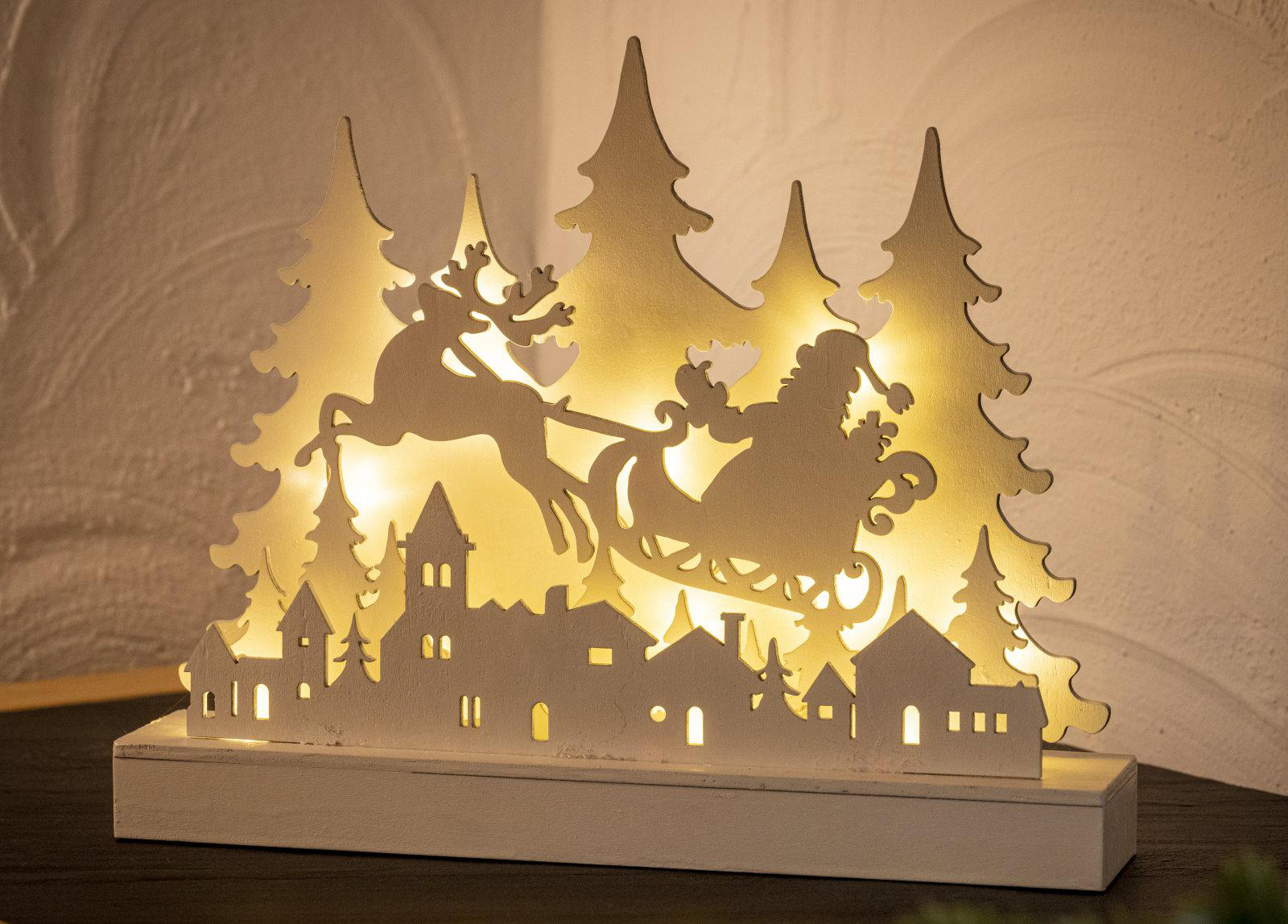 Weihnachtsdekoration mit Weihnachtsmann-Schlitten, Häusern und beleuchteten Bäumen.