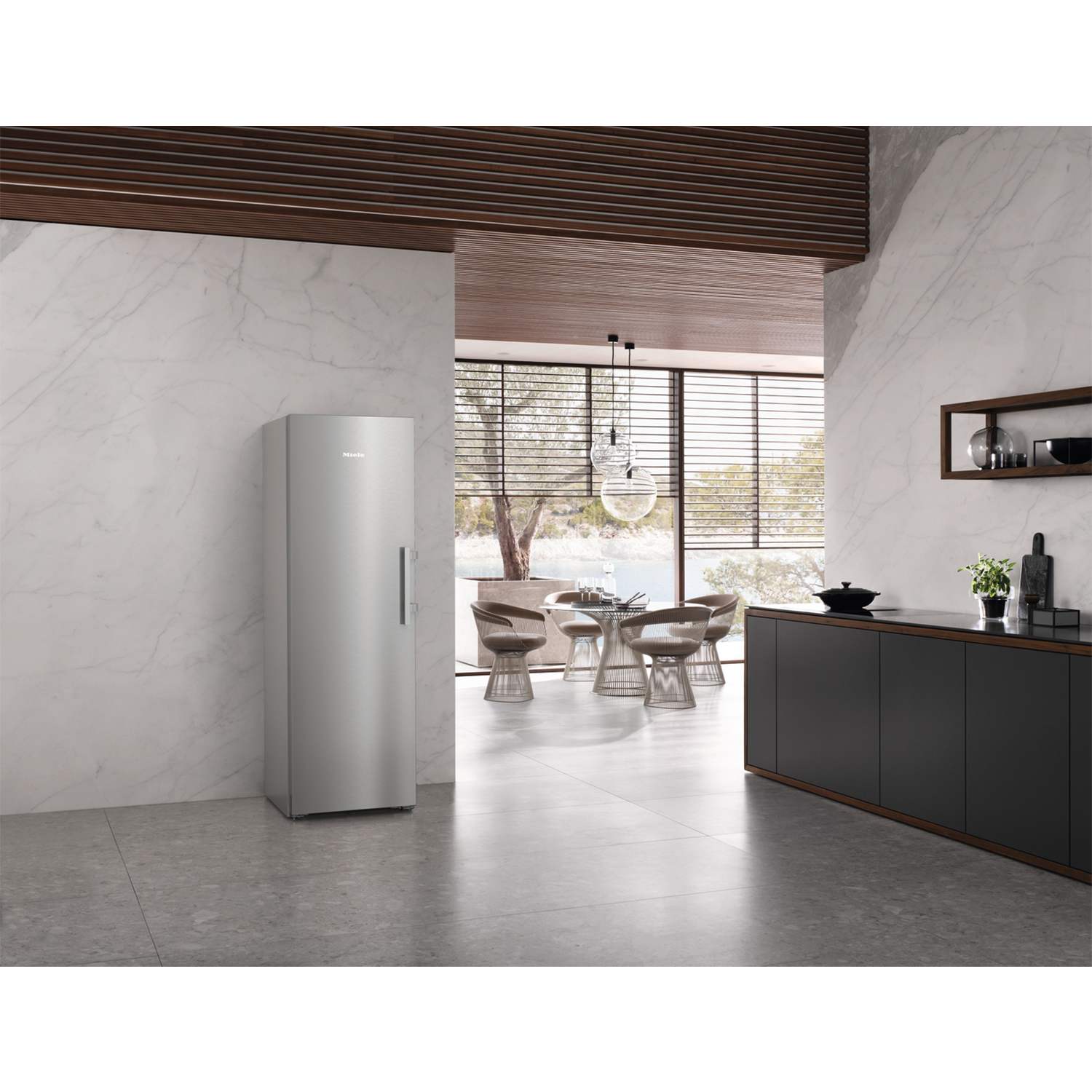 Frigorifero in acciaio inox in una cucina moderna con pareti in marmo e finiture in legno.