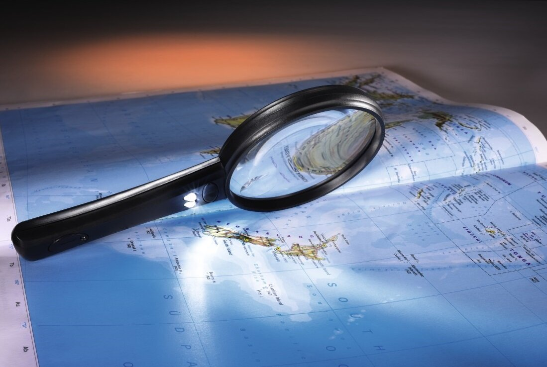 Czarna lupa na mapie, ze światłem oświetlającym mapę.