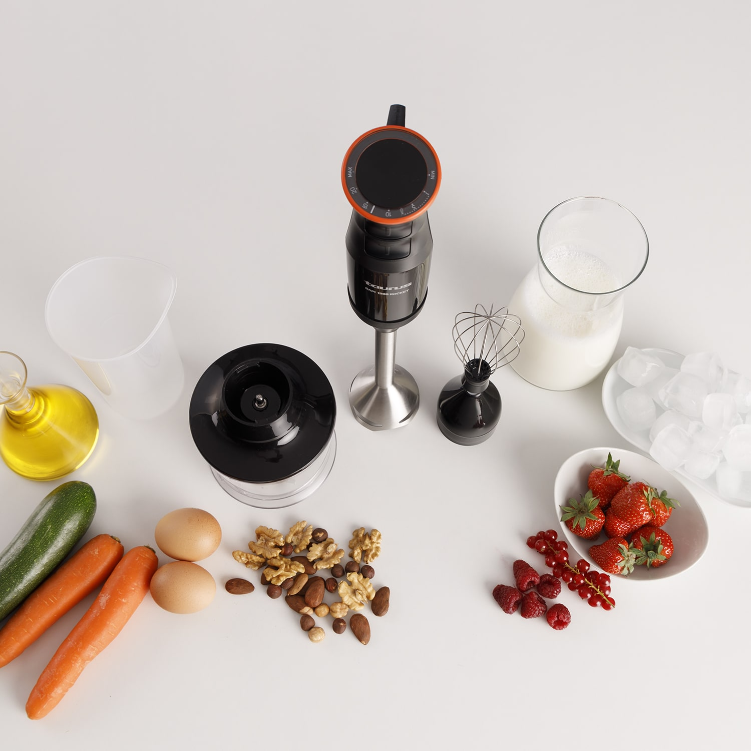 Ingredientes para batido: verduras, fruta, huevos, nueces y una licuadora sobre blanco.