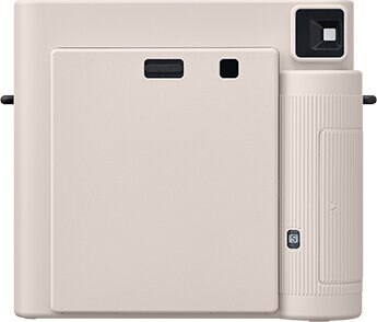 Jasnoróżowy aparat natychmiastowy z obiektywem po prawej, drzwiczkami i gniazdem na wkład.