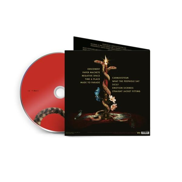 Piros címkéjű CD egy sötét hátterű kígyós-virágos mintájú füzet mellett.