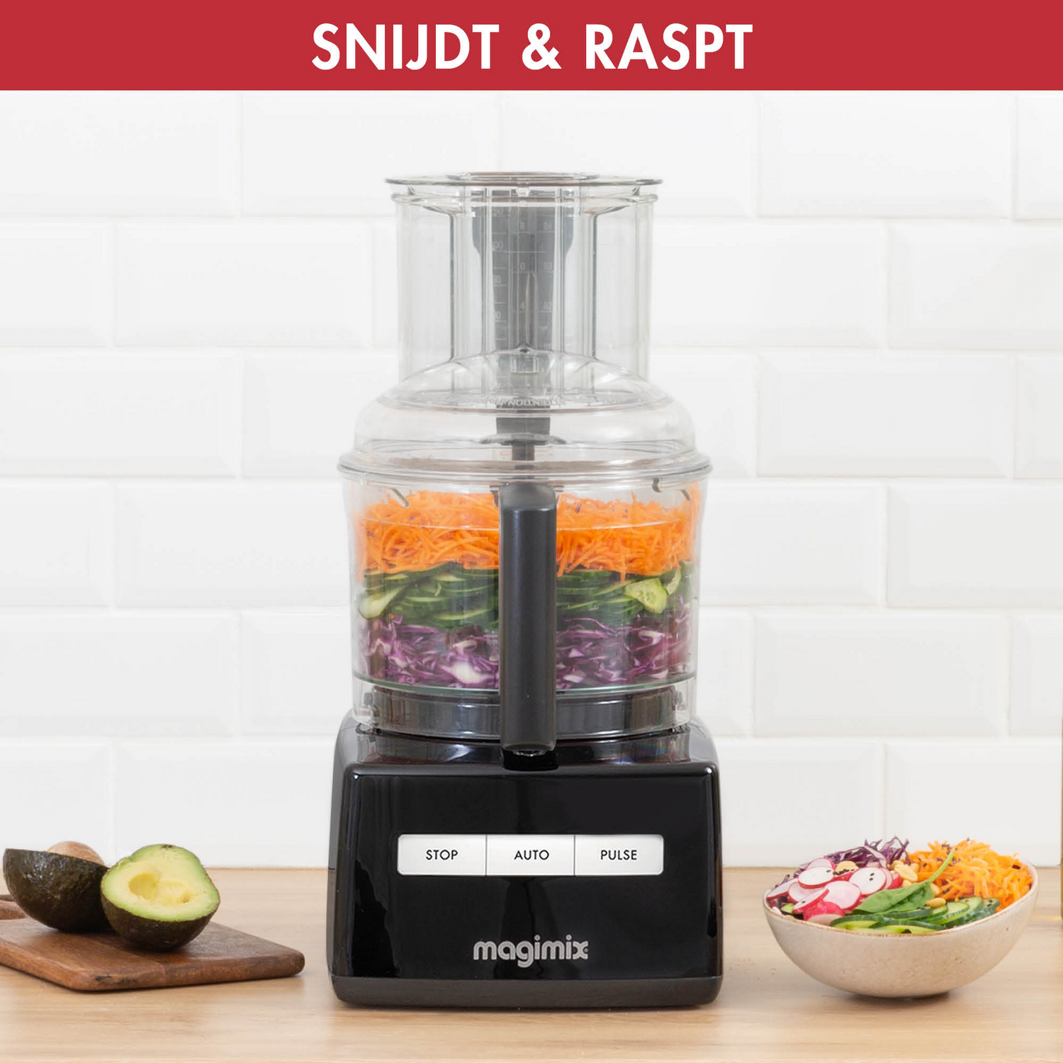 Food processor with vegetables, a bowl with salad, and avocado on a board.