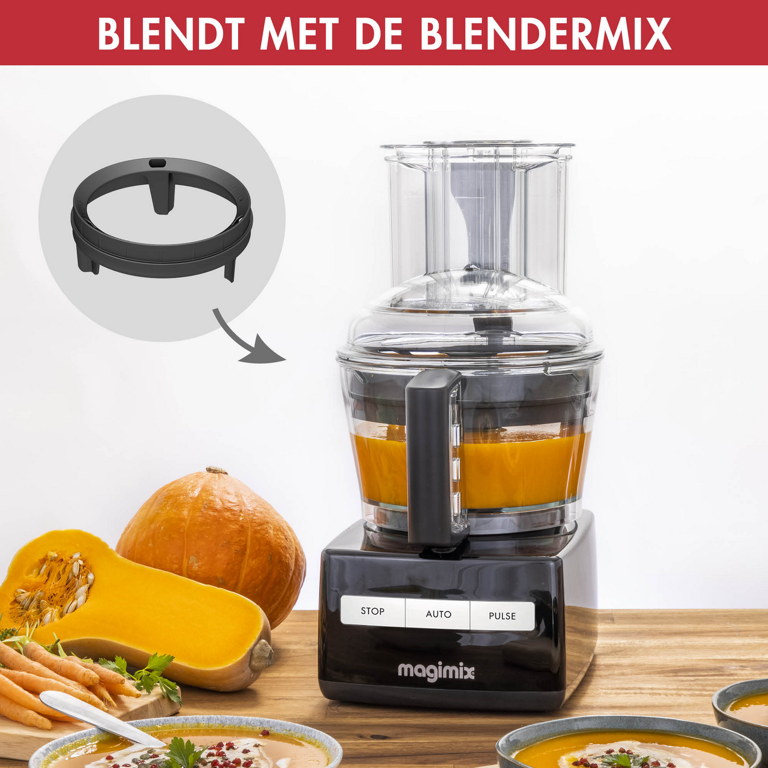 A food processor blends orange soup. Pumpkins, carrots, soup bowls are on the wooden table. A black part circled above.