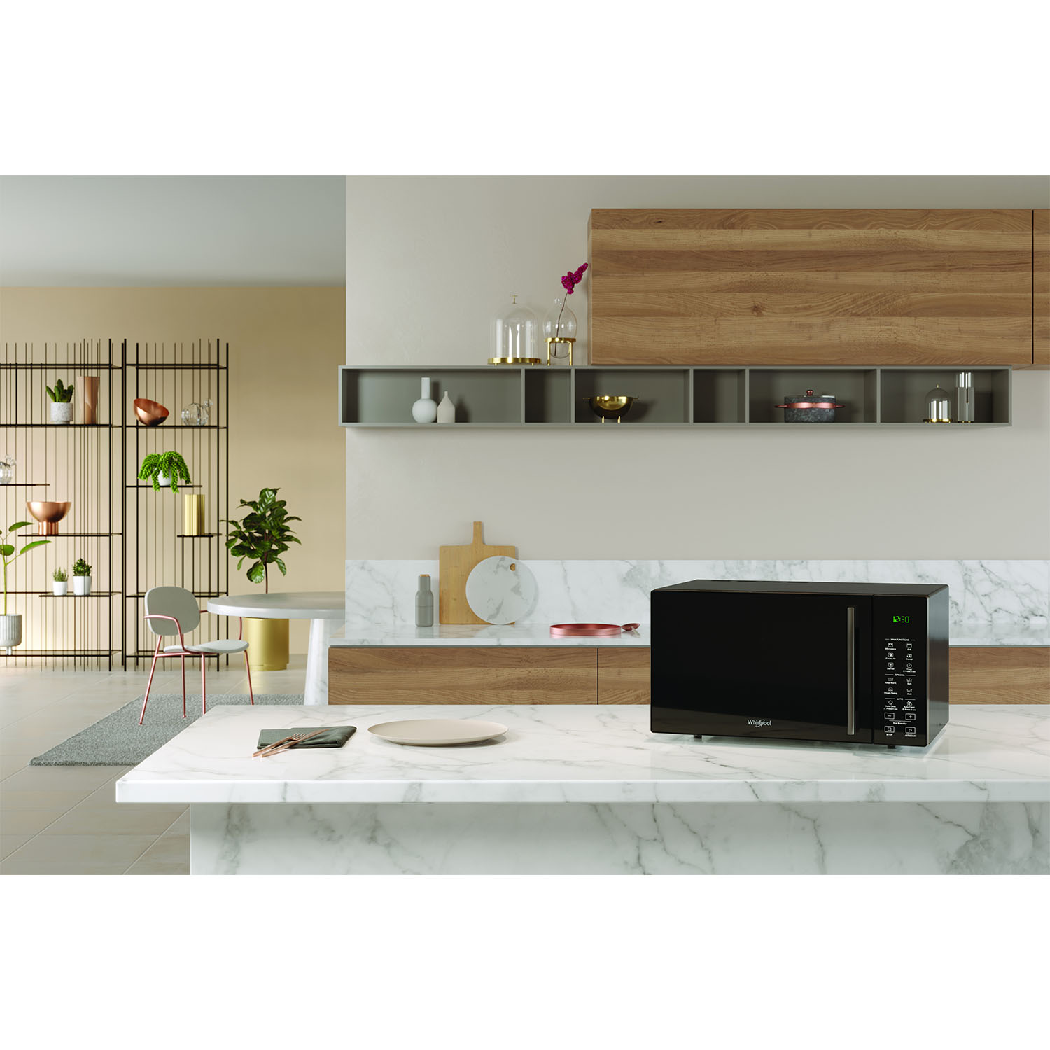 Interni cucina con microonde nero sul bancone. Muri beige, piano di lavoro in marmo, mobili in legno.