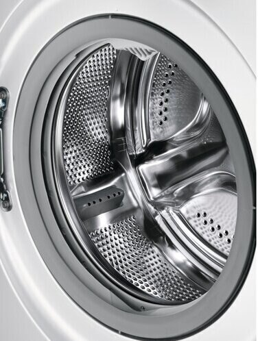 Zbliżenie na bęben białej pralki. Bęben jest wykonany ze stali.