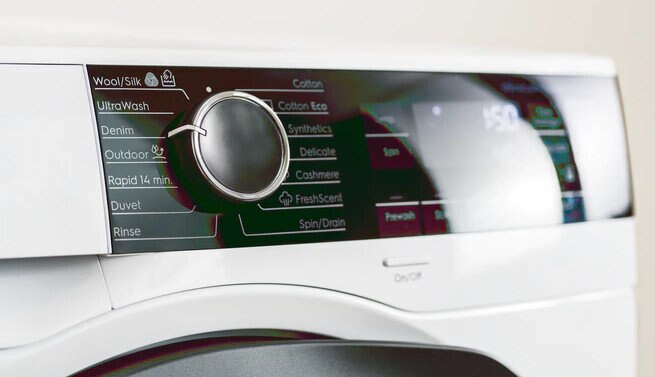 Szczegół panelu sterowania pralki. Pokazuje przyciski, pokrętło i wyświetlacz cyfrowy.