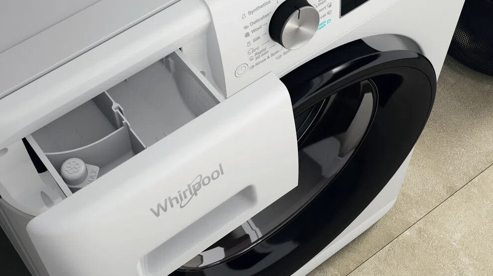 Zbliżenie szuflady na detergent białej pralki, otwartej i ukazującej przegródki.