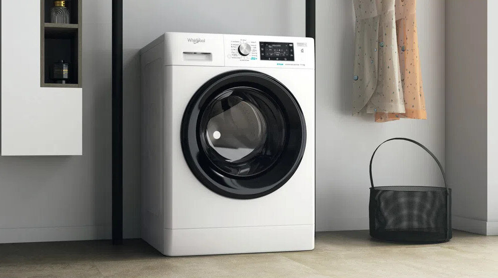 Biała pralka Whirlpool z czarnymi drzwiami, w pobliżu ubrań.