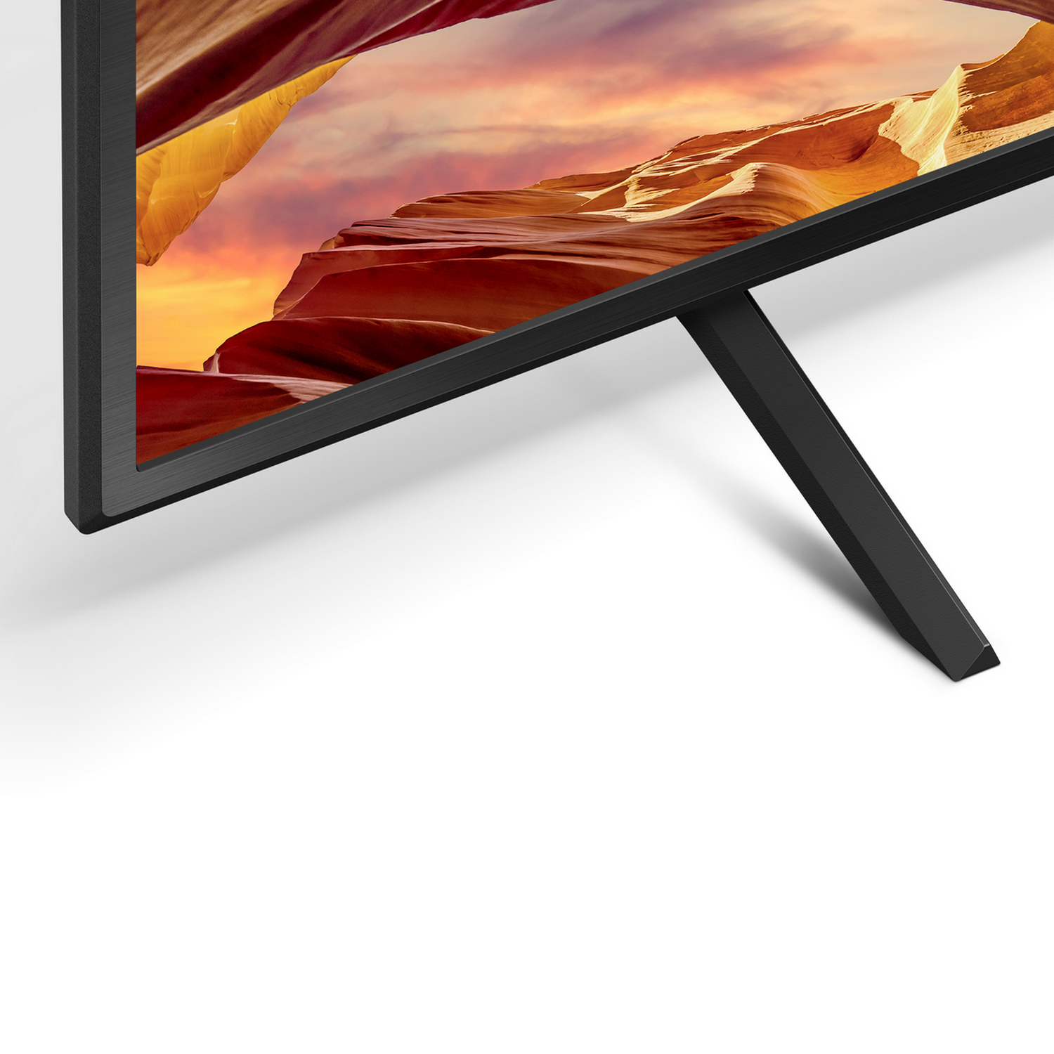 A close-up of a TV with a black frame and stand, against a white background.
