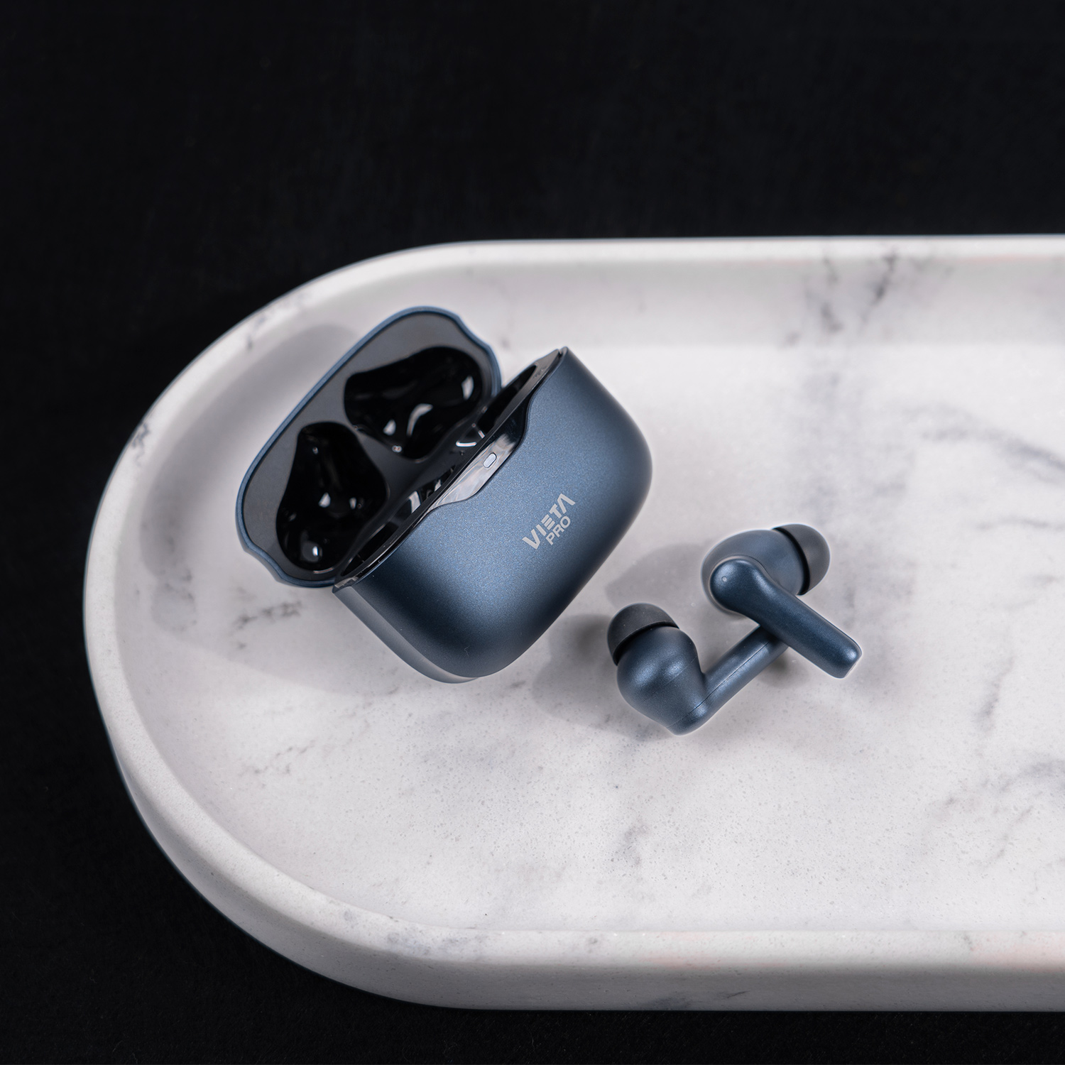 Un par de auriculares inalámbricos azules en su estuche de carga sobre una bandeja.