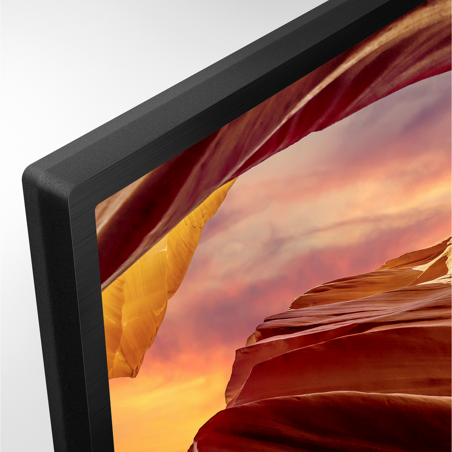 Close-up van de rand van een tv-scherm, met een levendige landschapsweergave met oranje en rode kleuren.