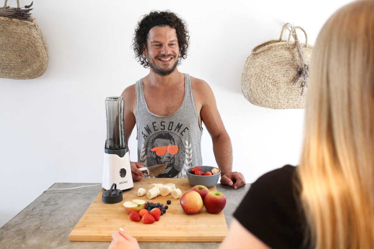 Mężczyzna uśmiechnięty, trzymający nóż i kobieta przy ladzie z jedzeniem.