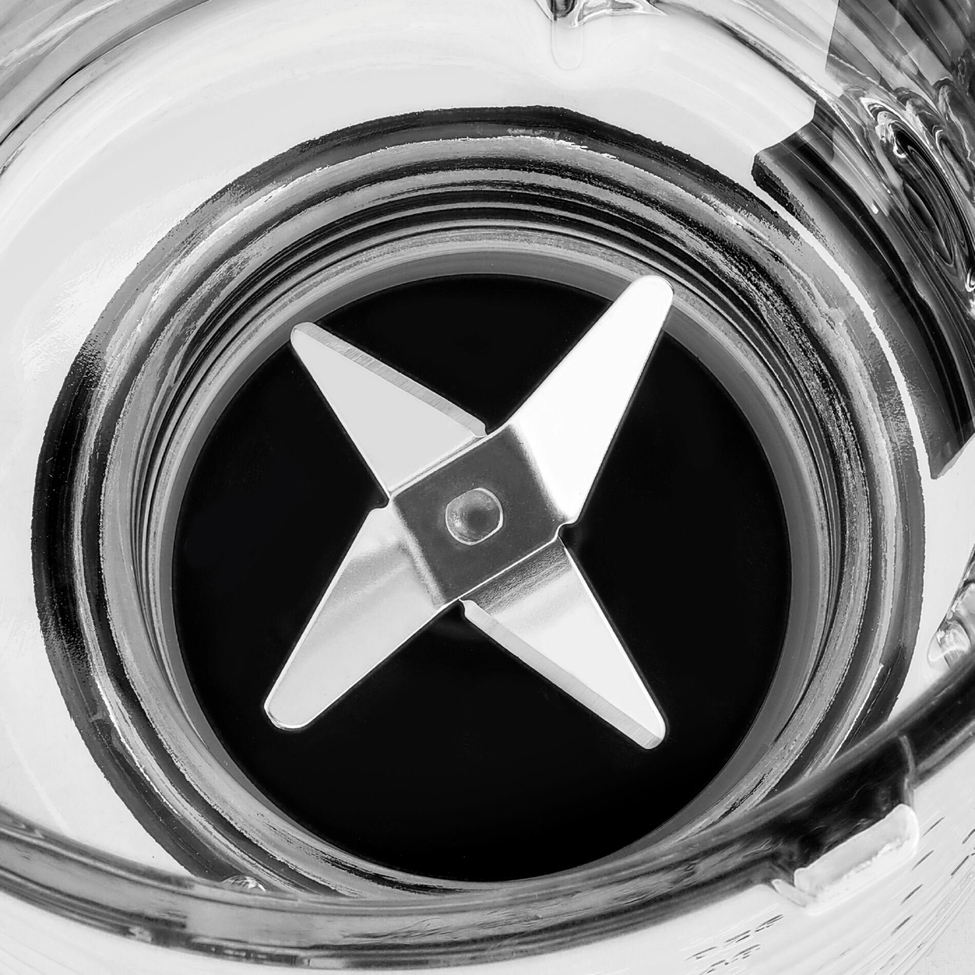 Zbliżenie wnętrza blendera, pokazujące ostrze ze stali nierdzewnej na dnie szklanego pojemnika.