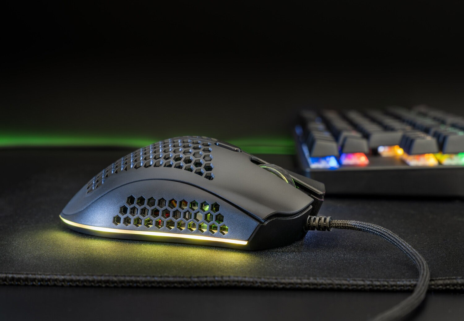 Mysz do gier na podkładce, z klawiaturą. Czarne tło i światła neonowe.