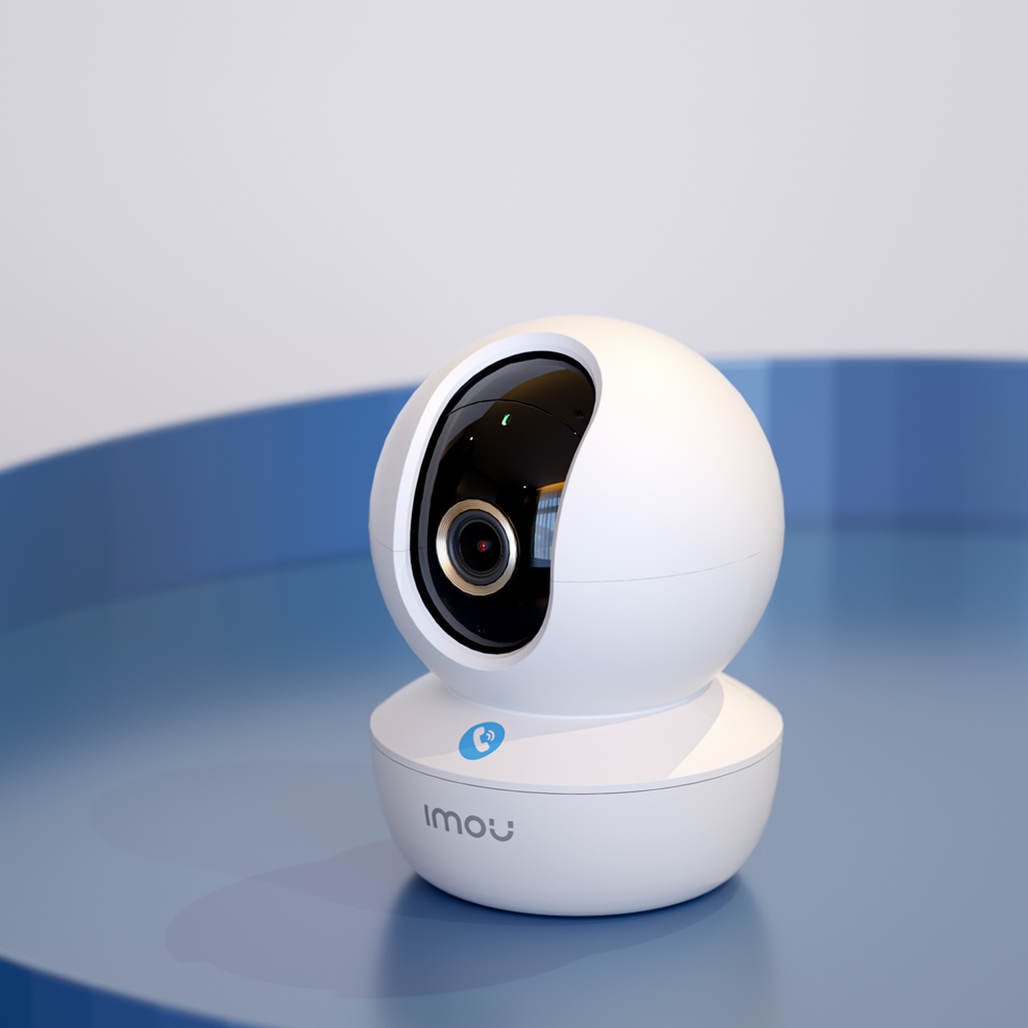 A white and black Imou security camera on a blue surface, with a round, swiveling camera head.