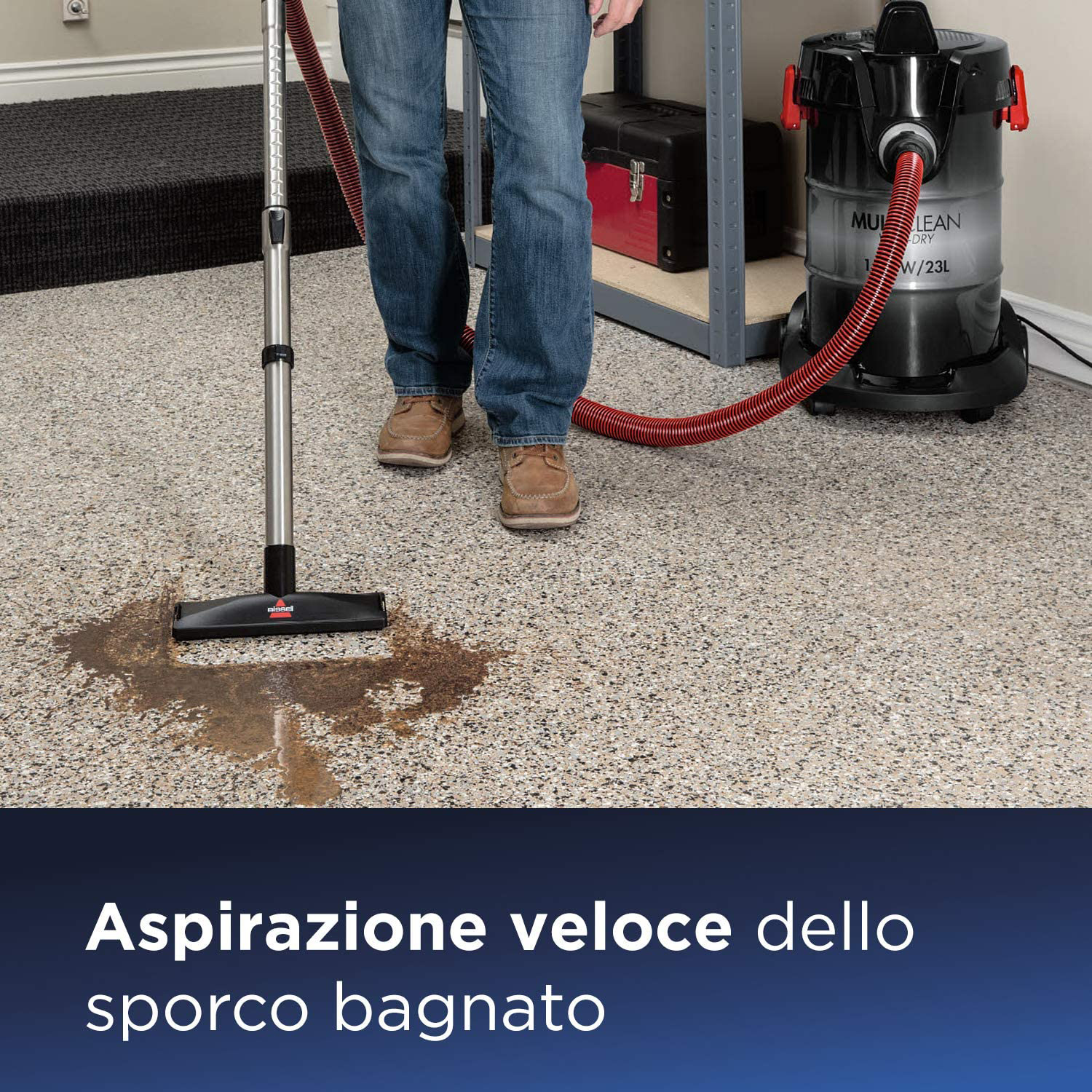 Un uomo che aspira un pavimento bagnato. C'è una macchia bagnata sul pavimento.