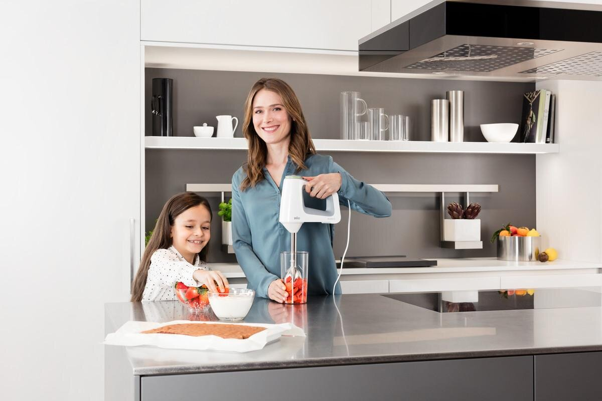 Kobieta i dziecko są w kuchni. Kobieta używa miksera.