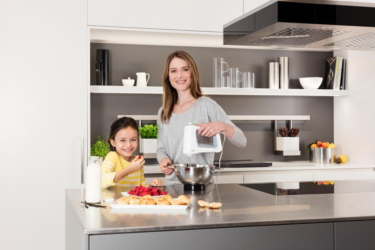 Kobieta i dziewczynka w kuchni. Kobieta używa miksera, dziewczynka je maliny. Wnętrze kuchni.