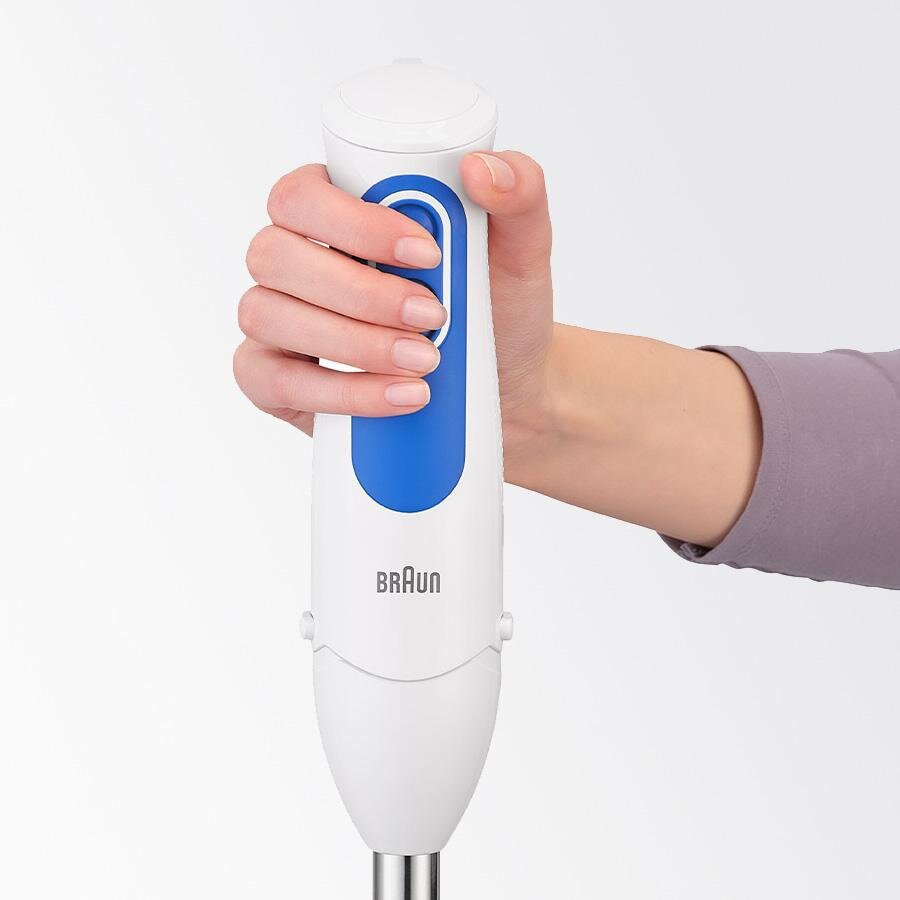 Ręka trzyma biało-niebieski blender ręczny Braun.