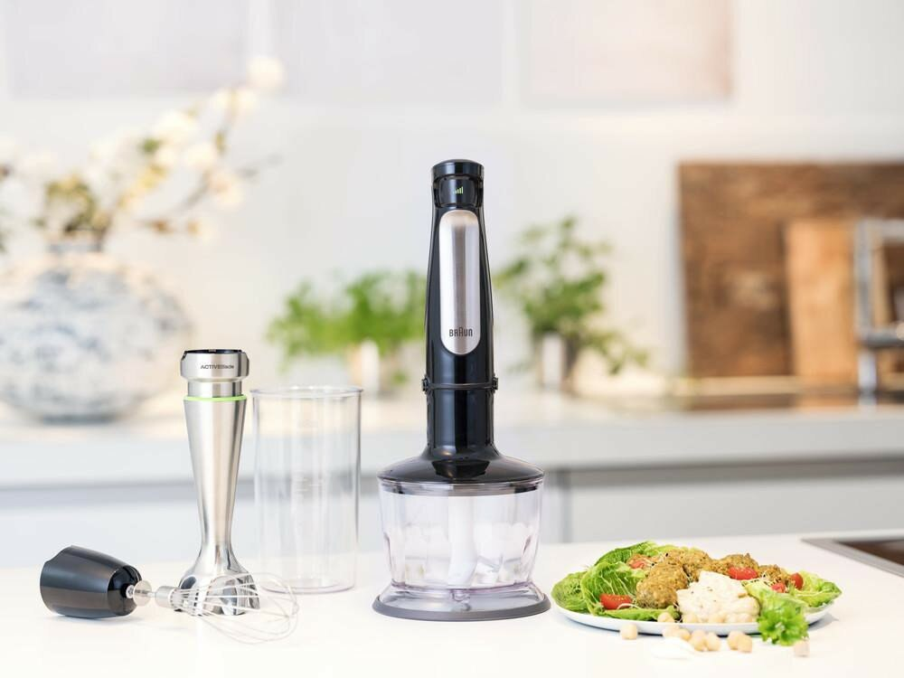 Czarny blender ręczny Braun z akcesoriami oraz falafelem i sałatką na talerzu.