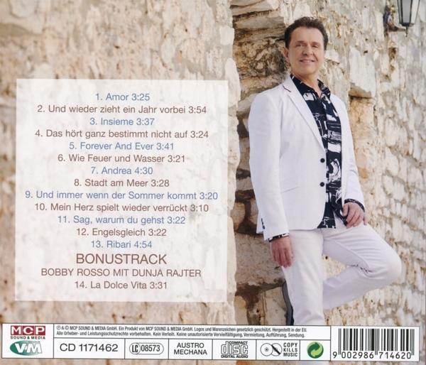 Mann steht an einer Steinmauer und hält einen CD-Cover.