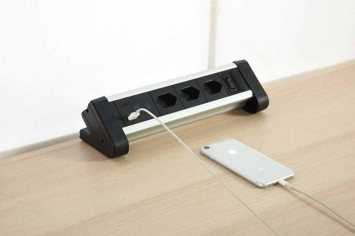 Steckdosenleiste mit Steckdosen und USB-Anschluss, in ein Telefon eingesteckt.