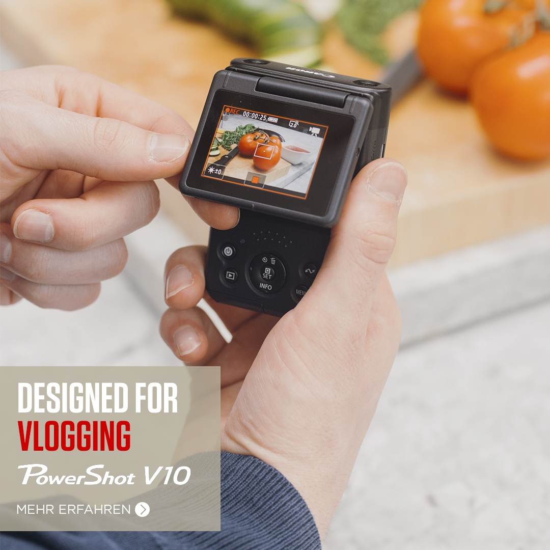 Person hält eine schwarze Vlogging-Kamera, Bildschirm zeigt Tomaten.