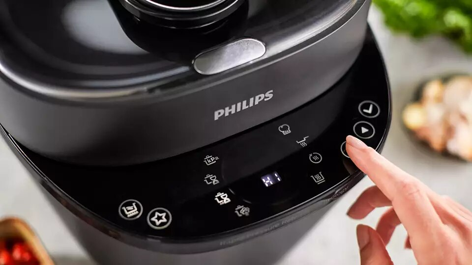 Interfejs urządzenia kuchennego Philips, dłoń dotykająca panelu sterowania.