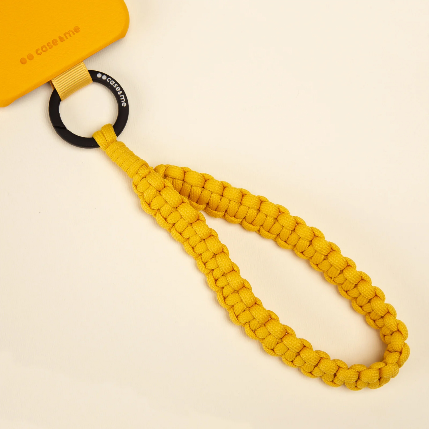 Cinturino per telefono intrecciato giallo con anello nero attaccato.