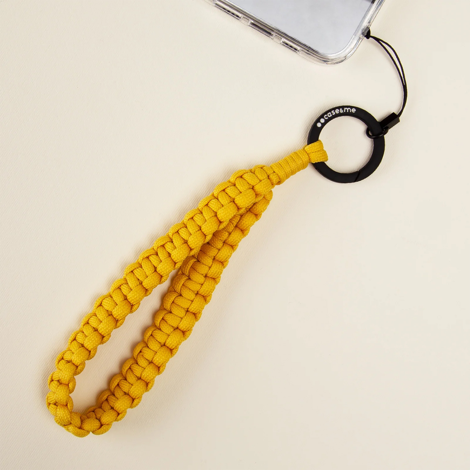 Un cinturino da polso giallo per telefono con un anello nero, su una superficie chiara.