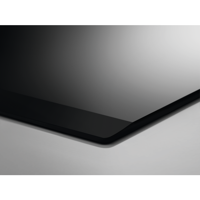 Primer plano de una superficie de vidrio negro. El fondo es gris.