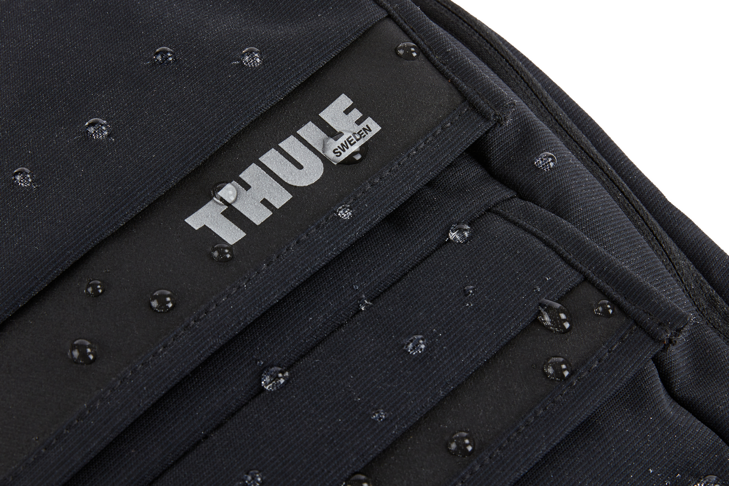 Bolsa negra con la palabra THULE en blanco y gotas de agua.