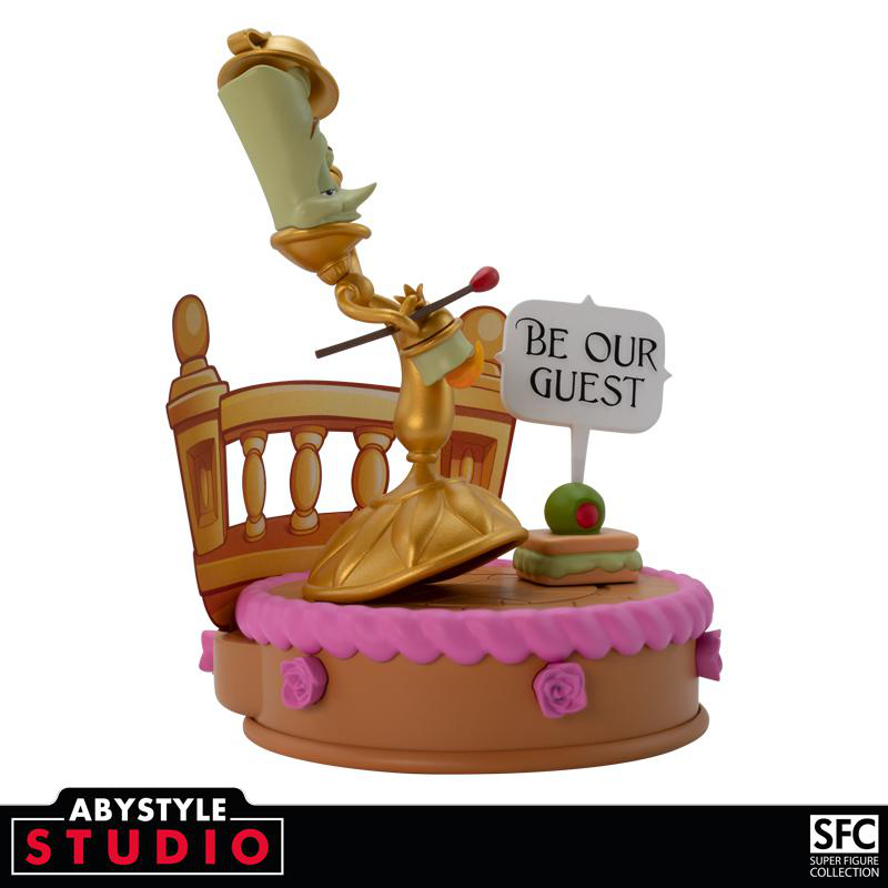 Eine Die Schöne und das Biest-Statue mit Lumiere, einem Kuchen und einem „BE OUR GUEST“-Schild vor weißem Hintergrund.