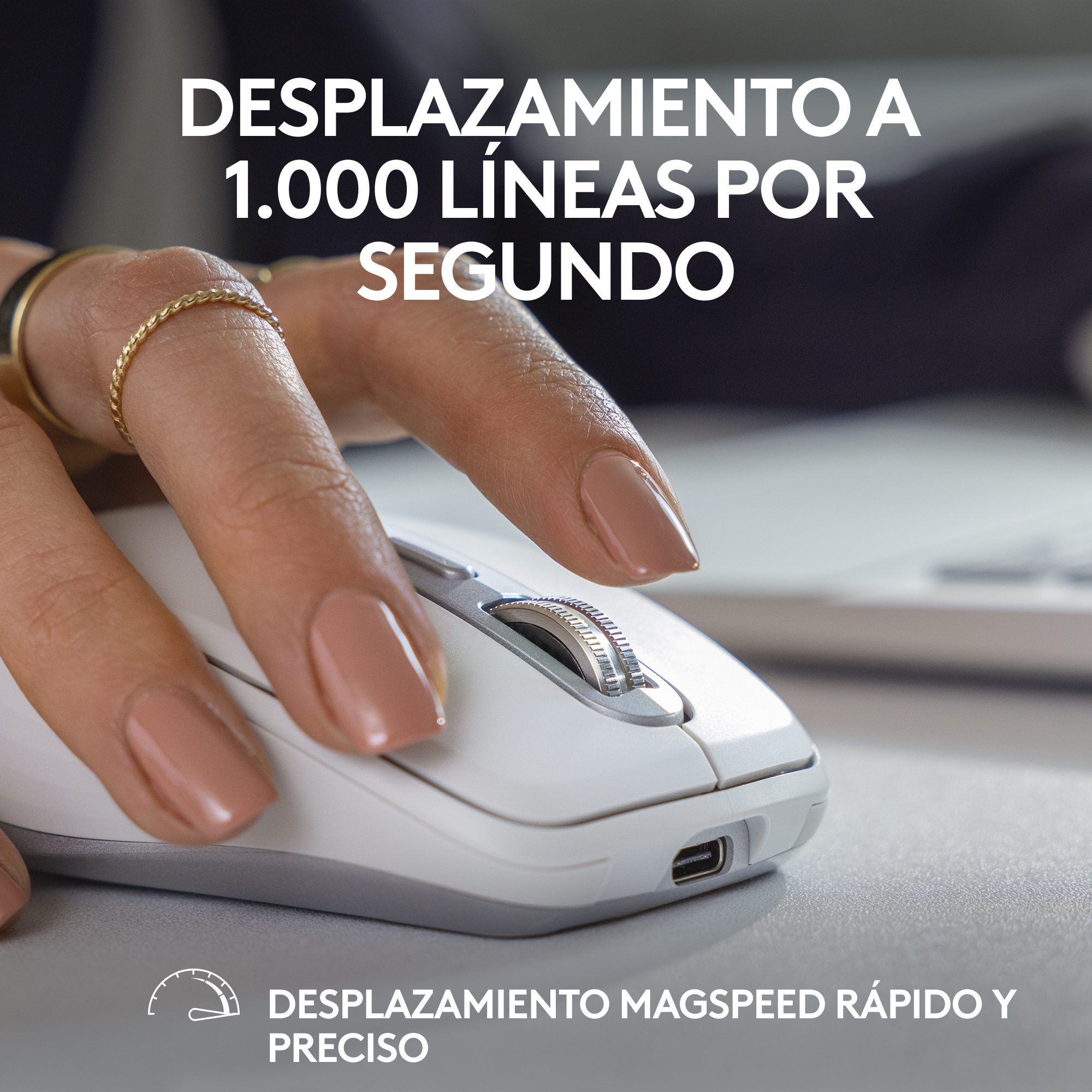 Una mano con un anillo toca la rueda de desplazamiento de un ratón de ordenador blanco.