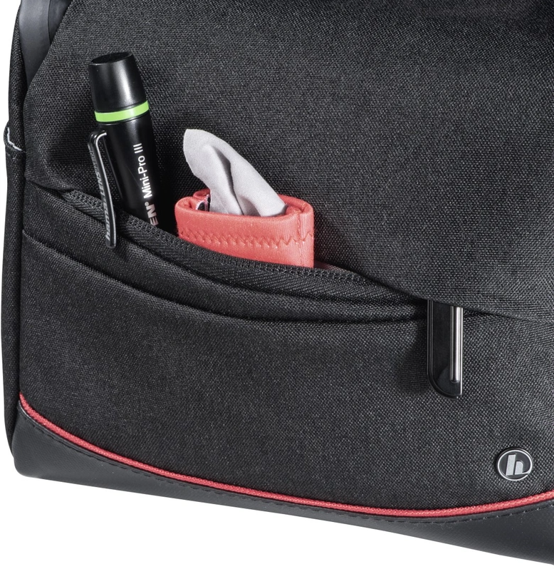 A black bag with a red trim. A pen, a tissue pack and other objects are in the side pocket.